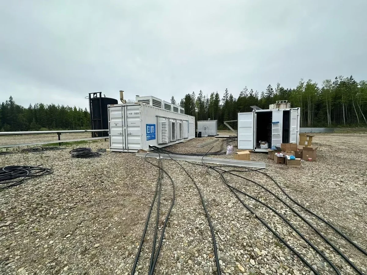 Containerized associated gas CHP power generation unit deployed at oilfield site with cables, white equipment containers, and forest backdrop