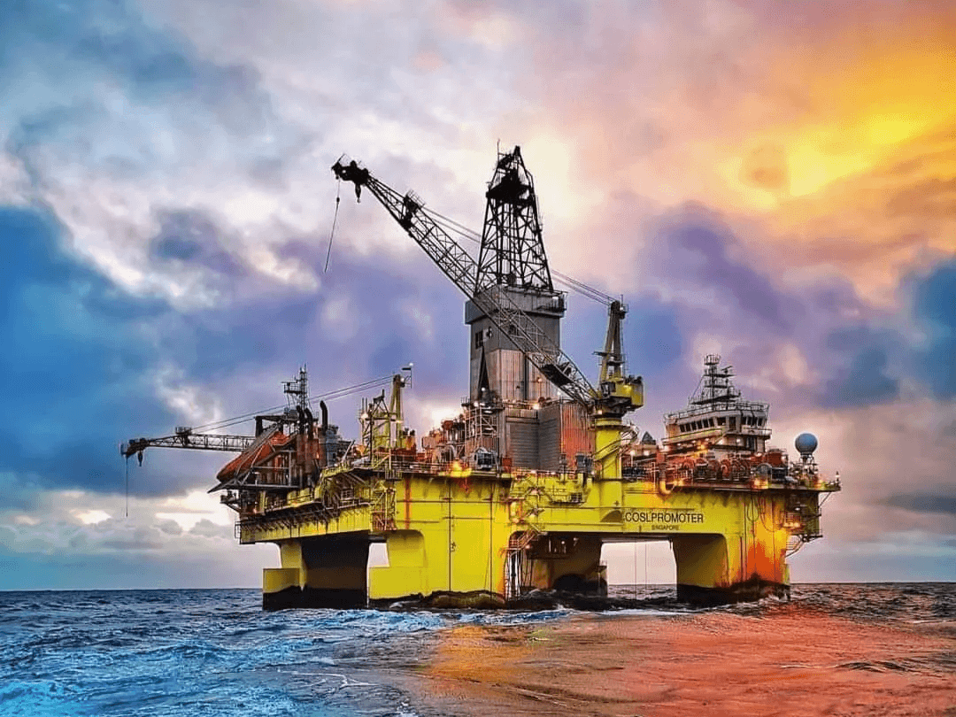 Large yellow offshore drilling platform at sunset, illustrating the need for effective offshore wax management solutions by Jingtao Energy.
